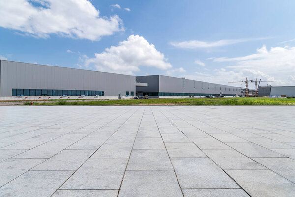 Empty square floor tiles and modern factory buildings and wareho