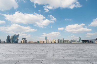Boş mermer zemin ve mavi gökyüzünün altındaki şehir manzarası.