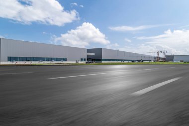 Yol asfaltı kaldırımı ve modern fabrika deposu.