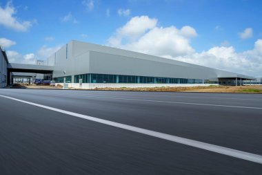 Yol asfaltı kaldırımı ve modern fabrika deposu.