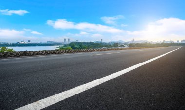 Boş asfalt yol meydanı ve mavi çizgilerin altında doğal manzara.