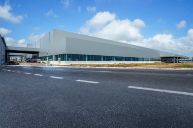 Yol asfaltı kaldırımı ve modern fabrika deposu.