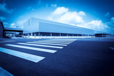 Yol asfaltı kaldırımı ve modern fabrika deposu.