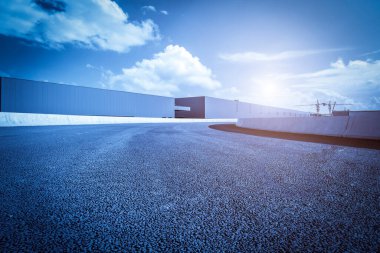 Yol asfaltı kaldırımı ve modern fabrika deposu.