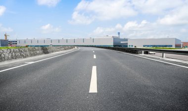 Yol asfaltı kaldırımı ve modern fabrika deposu.