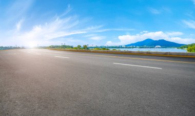 Boş asfalt yol meydanı ve mavi çizgilerin altında doğal manzara.