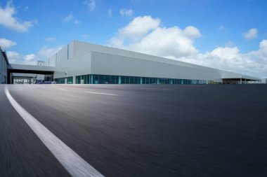 Yol asfaltı kaldırımı ve modern fabrika deposu.