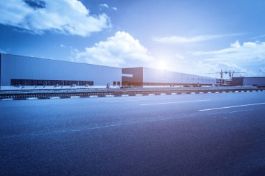 Yol asfaltı kaldırımı ve modern fabrika deposu.