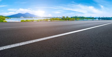 Boş asfalt yol meydanı ve mavi çizgilerin altında doğal manzara.
