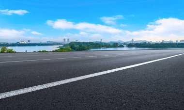Boş asfalt yol meydanı ve mavi çizgilerin altında doğal manzara.