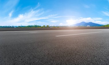 Boş asfalt yol meydanı ve mavi çizgilerin altında doğal manzara.