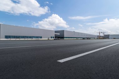Yol asfaltı kaldırımı ve modern fabrika deposu.