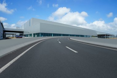 Yol asfaltı kaldırımı ve modern fabrika deposu.