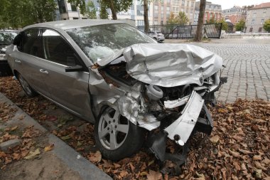 Brüksel, Brabant, Belçika 09 08 2025 gümüş bir sedan bir kazada ağır hasar gördü. Sonbahar yapraklarıyla kaplı bir caddeye park edilmiş..