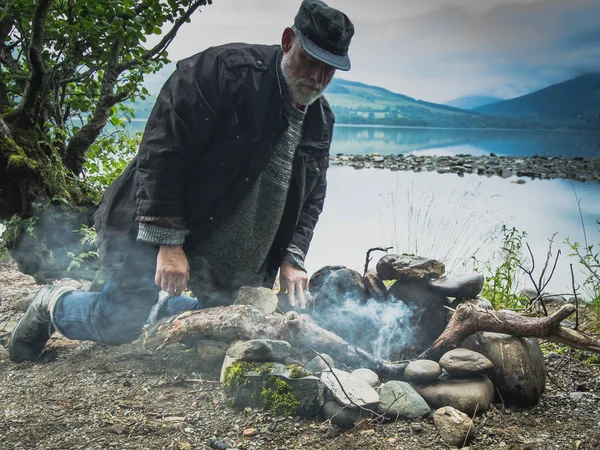 L'Écosse. Voyageur mature allumé un feu près du lac . — Photo