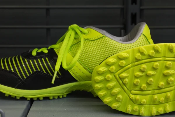 Modern sports shoes in  black  and yellow-green vibrant color on the gray background