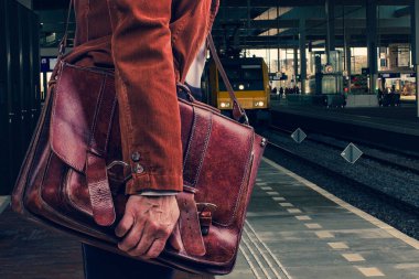 İş yolcu tren Amsterdam Tren İstasyonu platformu için bekleyen gerçek deri çanta ile kadife kahverengi ceketli