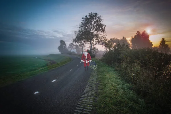 Weihnachtsmann Mit Weihnachtsbaum Auf Der Landstraße Dunkel Sonnenuntergang — Stockfoto