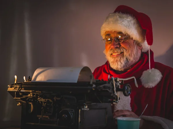 Mutlu Noel Baba karanlık onun rahat oda oturma ve komik bir mesaj yazma portresi.