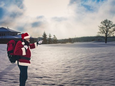 Karla kaplı sahada ayakta ve uzak ufuk parmak ile işaret sırt çantası ile sportif Noel Baba. Etkin sağlıklı yaşam tarzı ve Turizm kavramı.
