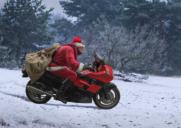 Noel Baba hediye, bir torbayla kırmızı bir motosiklet sürücüleri hızlı karla kaplı alan.