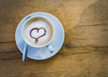 Bir fincan kahve ile bir kalp bir masada ahşap hafif kahverengi kopya alanı. Sevgilerle, Sevgililer günü kavramı.