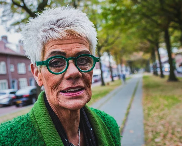 portrait of a senior woman with wrinkles on the skin in the autumn street, outdoor shot