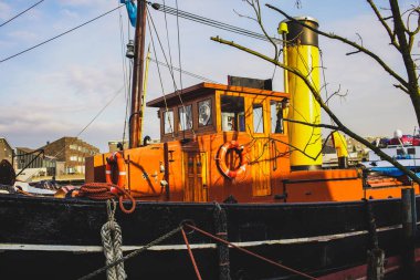 Bir nehir kıyısında sarı boru ile eski turuncu ağır tekne