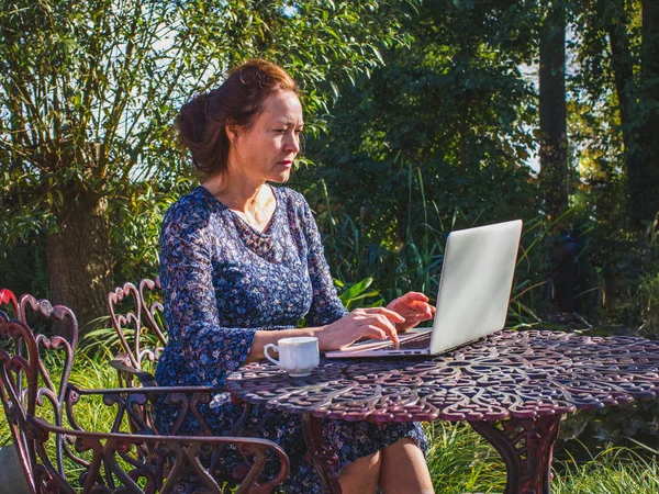 Femmes d'affaires de 50 ans travaillant dans le jardin avec un ordinateur portable co — Photo