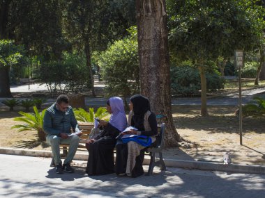Lecce, Italya 23 Nisan 2018: geleneksel giyim ve siyah adam Lecce halk parkında oturan Iki Bayan.