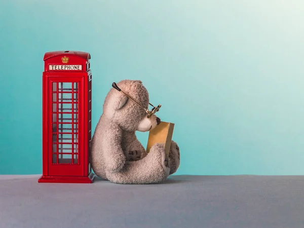 Плюшевый мишка сидит рядом с телефонной будкой в Лондоне и ищет — стоковое фото