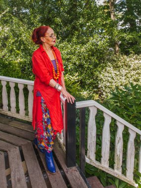 Kırmızı parlak giysiler içinde Modern sıradışı üst düzey kadın ayakta bir 