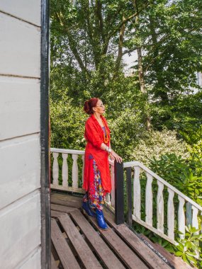 Parlak giysiler içinde Olgun oryantal kadın ahşap demiryolu pozlar