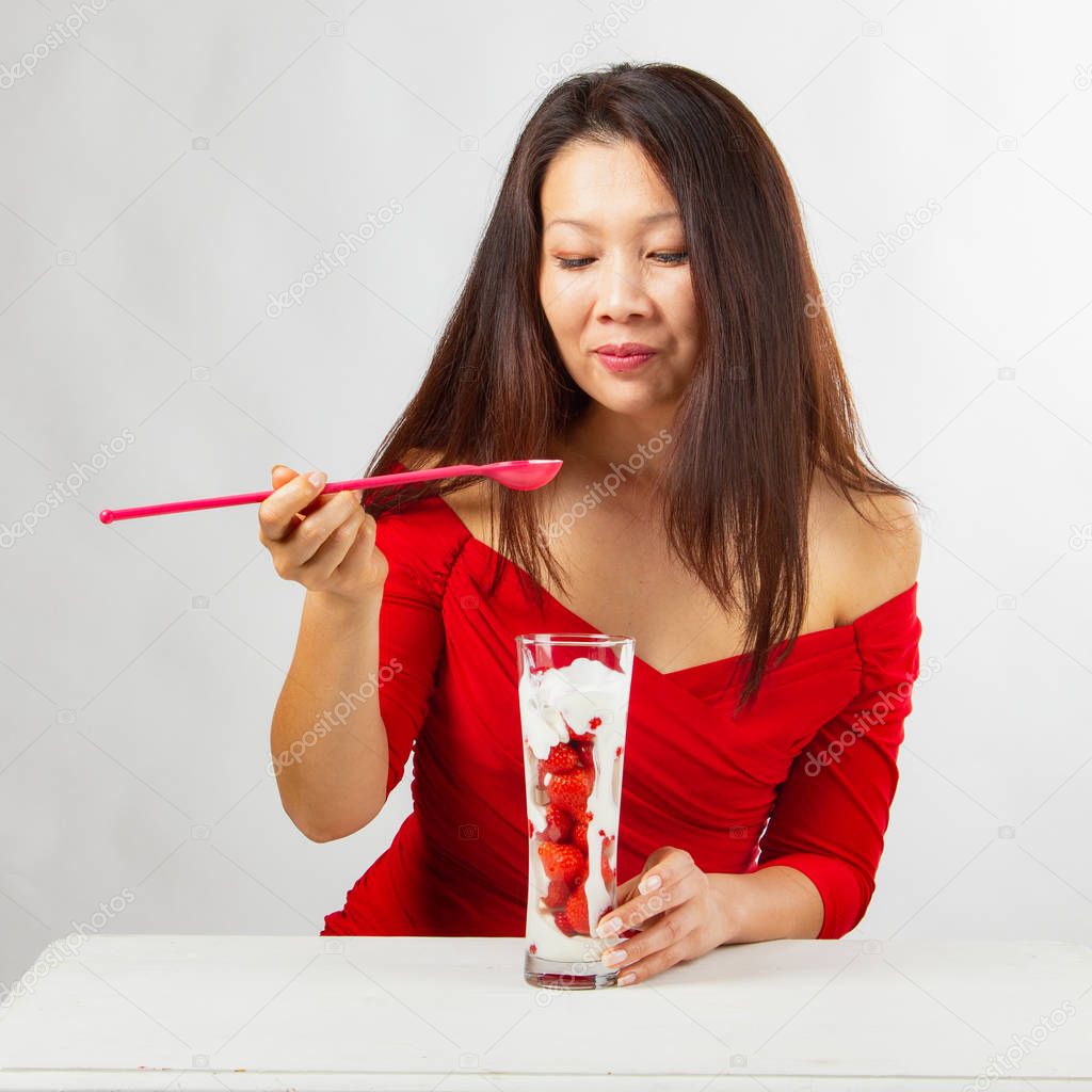 fashionable asian woman savoring of delicious strawberry-yoghurt