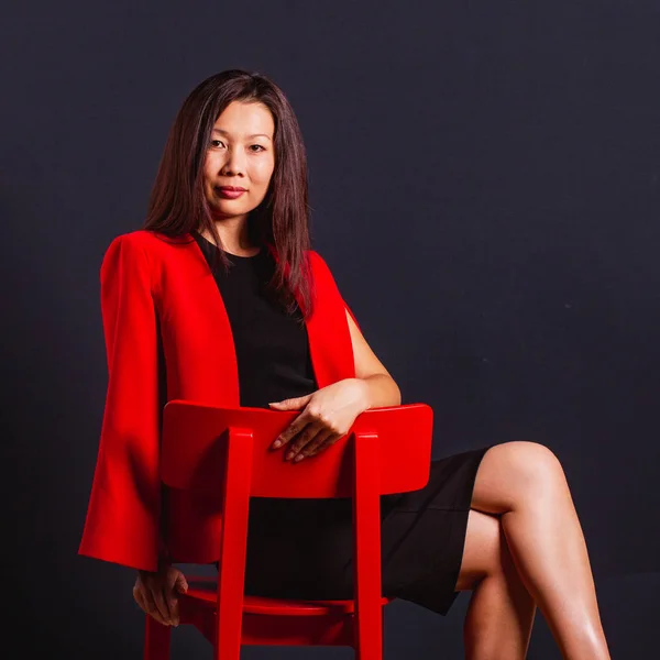 美しいアジアのビジネスウーマンは、赤い椅子に座って見て — ストック写真