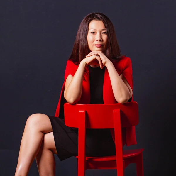 Belle femme d'affaires asiatique assis sur une chaise rouge et regarde — Photo