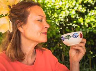 Zevkli çay içen neşeli orta yaşlı bir kadının portresi