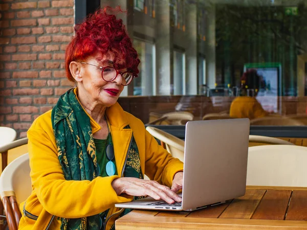 Attrayant mature femme est assis dans un café à l'aide d'un ordinateur portable com — Photo