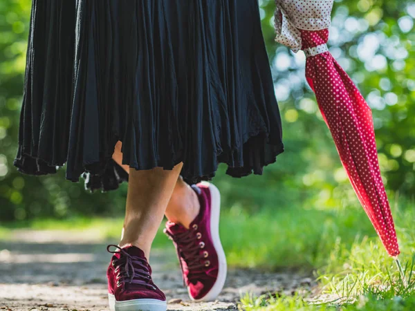 Female legs in maroon schoes stand on the trail among green gras — Stock Photo, Image