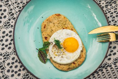 Düz ekmek pizzalı sahanda yumurta ve mavi-beyaz arka plan. Tablonun üst görünümü, rustik biçim.