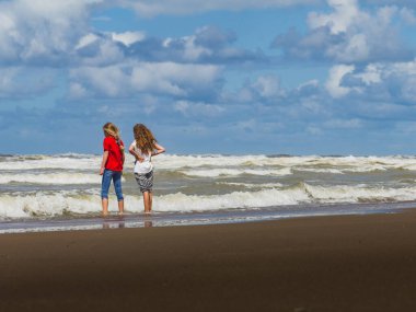 KATWIJK - NETHERLANDS - 10 Ağustos 2016: Yaz mevsimi, güneşli bir günde Katwijk sahilinde oynayan iki çocuk. Hollanda.
