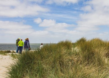 SCHARENDIJKE - NETHERLANDS - MAY, 17, 2018: Kuzey Denizi 'ne bakan kum tepelerindeki çeşitli insanlar.