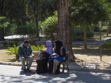 Siyahi kadın ve erkek şehir parkında ellerinde belgelerle oturuyor..