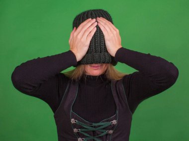 Genç bir kadın örgü bir şapkayla yüzünü örtüyor ve elleriyle başını tutuyor. İzolasyonu kutsa.