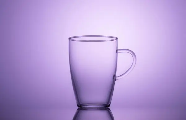 Kopp glas på lila bakgrund. — Stockfoto
