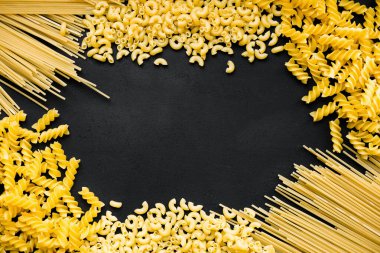 Çiğ fusilli, boru rigati ve makarnayı kopyalama alanı olan siyah tahta üzerinde..