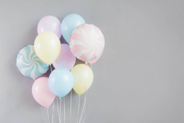 Gri arka planda pastel renkli bir grup balon..