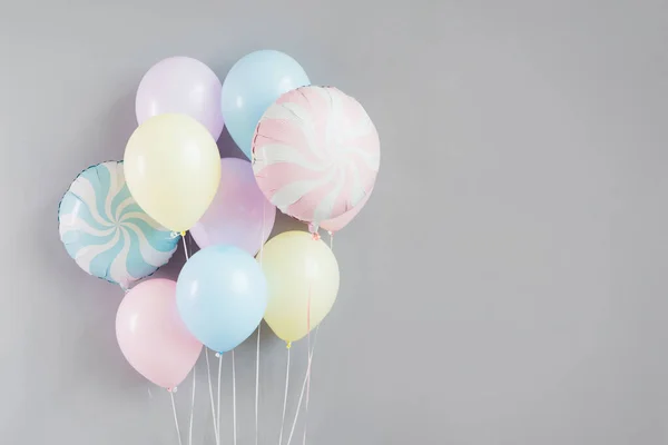 Gri arka planda pastel renkli bir grup balon..