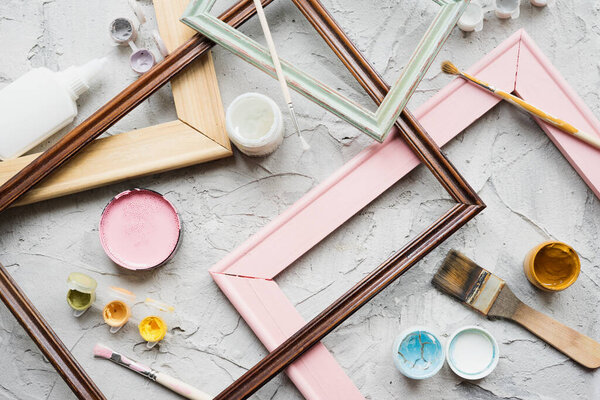 Several wooden frames, paint brushes and paint cans on gray gray background. Workshop of the artist.
