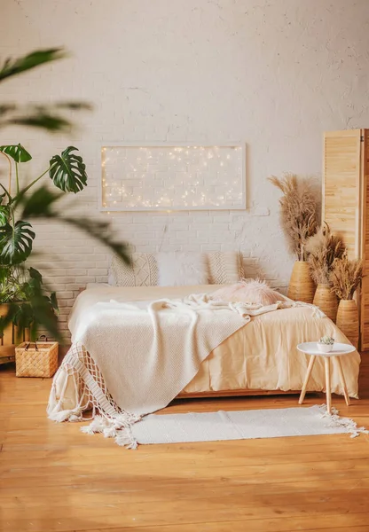 Parlak boho tarzında şık bir yatak odası. Tekstil bolluğu ve canlı ev bitkileriyle dolu rahat, modern bir iç mekan..
